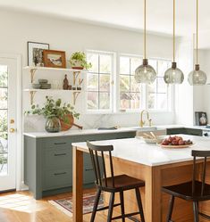 a kitchen with an island in the middle and three stools at the counter top