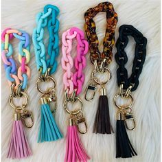 four different colored tassels are shown on a white furnishing area, with one keychain in the middle