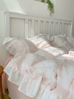 a bed with pink and white comforters on top of it next to a wooden table