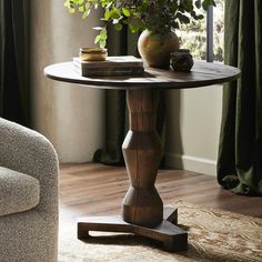 a wooden table with a plant on it in front of a window and a chair