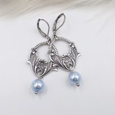 For this pair of new earrings - I used light baby pastel blue top quality crystal cored pearls, which dangle below antique silver plated brass stamped metal connectors.  These sweet little flower basket pieces are so well done with lots of gorgeous antiqued silver details.  The ear wires are stainless steel lever backs, bringing the total length to 2 1/4 inches.  Thank you - shop my collection here:  www.etsy.com/shop/hhjewelrydesigns