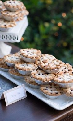 several pies are sitting on trays next to each other at a wedding reception