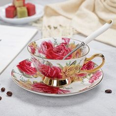 a cup and saucer on a table with coffee beans