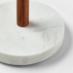 a white marble table with a wooden handle on the top that is standing in front of it