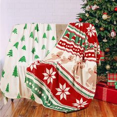 a christmas blanket sitting on top of a couch next to a christmas tree and presents