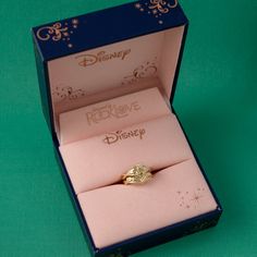 a gold ring in a pink box with the disney logo on it's side