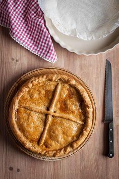 a pie sitting on top of a wooden table next to a knife