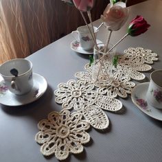 a table topped with two cups and saucers filled with pink flowers next to each other