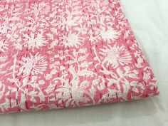 a pink and white bed spread on top of a bed next to a pillow case