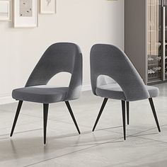 two grey chairs sitting next to each other on top of a tile floor in front of a white wall