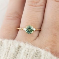 a woman's hand with a ring on her finger and a green stone in the middle