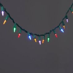 a string of multi - colored christmas lights on a gray background