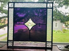 a purple stained glass window sitting on top of a wooden table next to a tree