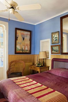 a bed room with a neatly made bed and paintings on the wall