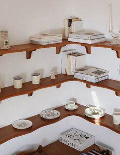 a corner shelf with books and cups on it