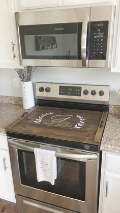 a kitchen with stainless steel appliances and white cabinets, including a microwave above the stove