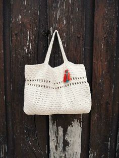 a crocheted bag hanging on a wooden door with an orange pin in it