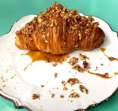 a croissant on a plate with caramel sauce drizzled over it