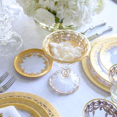 the table is set with gold and white dishes