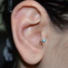 a woman's ear with a tiny turquoise stone in the middle