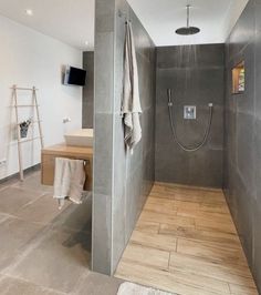 a walk in shower sitting next to a wooden table and sink on top of a hard wood floor