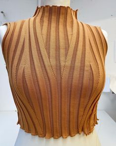 a mannequin wearing a brown top with pleating on the front and back