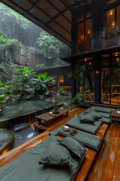 there are many pillows on the floor in front of some water and trees with plants