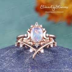 a ring with an oval stone surrounded by leaves and diamonds on top of a rock