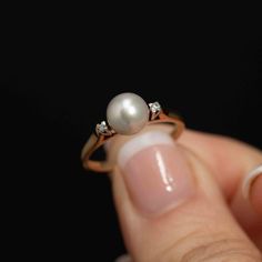 Elevate your style with this exquisite Vintage Cultured Pearl Ring adorned with two dazzling accent diamonds on either side. The centerpiece is a lustrous 7.20mm cultured pearl, exuding elegance and sophistication. Flanking the pearl are two, 2mm diamonds which add a touch of brilliance to this classic piece. Set in a beautifully scalloped base, the pearl is positioned prominently, creating a stunning focal point. The ring is marked with 14K and 18K stamps, along with a distinct maker's mark, si Timeless Diamond Pearl Ring With Prong Setting, Classic Brilliant Cut Diamond White Pearl Ring, Timeless Pearl Ring With Diamond Accents, Classic Pearl Ring With Prong Setting, Classic Pearl Ring With Prong Setting In Diamond White, Classic White Gold Pearl Ring With Diamond Accents, Classic Diamond White Pearl Ring With Prong Setting, Timeless Pearl Ring With Brilliant Cut For Wedding, Timeless Diamond Pearl Ring With Center Stone