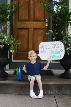 a little boy sitting on the steps holding up a sign