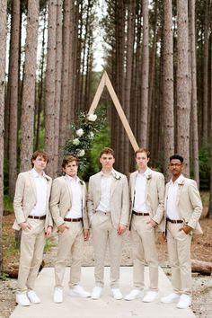 a group of young men standing next to each other in front of some tall trees