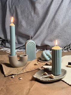 three candles sitting on top of a table next to a plate with a candle holder