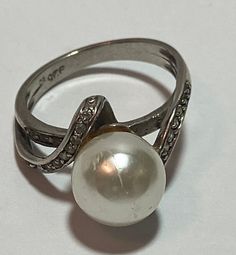 This is a beautiful, vintage, genuine cultured pearl, diamonds and sterling silver ring. The ring is a size 7 1/2 and could easily be resized by a jeweler if needed smaller or larger.  The cultured pearl is about 1/2" (about 12mm) and is stunning. There are round-cut, prong-set diamonds set in the two bands on the ring. Please note, one diamond is missing and the ring has been priced with this in mind. The ring is stamped 925 EC and weighs about 4.6 grams. Gorgeous! See pictures for details.  Ch Silver Rings With Diamond Accents And Pearl, Silver Pearl Rings With Diamond Accents, Vintage White Gold Pearl Ring With Diamond Accents, Elegant White Gold Pearl Ring Stamped 925, Elegant Silver Pearl Ring Stamped 925, Classic Silver Pearl Ring For Formal Occasions, Vintage Pearl Ring As Gift, Classic Silver Pearl Rings, Elegant Formal Pearl Ring Stamped 925