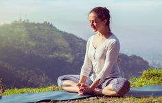 a woman sitting on top of a hill doing yoga