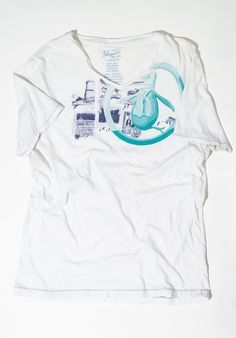 This is a fabulous The Original Penguin Munsingwear T Shirt.  The tshirt has a v-neck. The shirt itself is white.  The graphic is of white and navy blue with a large Penguin logo stamped onto the left side of the shirt in varying shades of teal blue. The hem of the shirt and the shirt sleeves are trimmed with blue thread. Tag: Penguin Size: Large Measurements: Chest: 20" Sleeve: 9" Large: 28" For all vintage treasures: We love finding unique pieces for you, and we disclose as much detail as possible in our listings. However, since these are pre-loved items, occasional minor imperfections might go unnoticed. If you'd like more photos, specific measurements, or a video to ensure a perfect fit, feel free to contact us before buying! We offer first-come, first-served vintage finds. Additional White V-neck Top With Sublimation Print, White Graphic Print V-neck Top, White Cotton V-neck T-shirt, Graphic Tee V-neck T-shirt With Screen Print, V-neck Graphic Tee With Screen Print, Relaxed Fit V-neck T-shirt With Graphic Print, White V-neck T-shirt With Letter Print, Cotton V-neck Top With Screen Print, V-neck Graphic Tee With Graphic Print