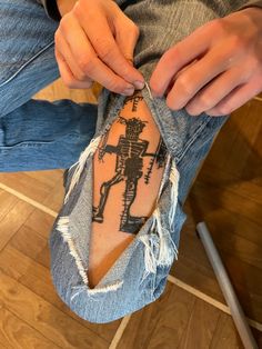 a person with a tattoo on their arm holding onto a pair of ripped up jeans