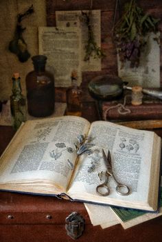 an open book sitting on top of a wooden table next to a pair of scissors