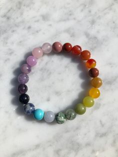 Introducing our exquisite handmade Chakra Gemstone bracelet. This stunning design features a combination of Red Jasper, Orange Carnelian, Red and Yellow Aventurine, Lemon Jade, Peridot, Green Moss Agate, Green and Blue Spot Jasper, Purple Dyed Chalcedony, Kunzite, Blue Magnesite, Goldstone, and Rhodonite. Each stone in this design is a a celebration of the vibrant colors found in nature and each holds its own unique hue, representing different aspects of the natural world. Beads are 8mm each, on a stretch cord which is double strung for durability. Each bracelet is carefully placed on a selenite plate overnight to cleanse and recharge its energy, ensuring it has the highest vibrational quality.  From the grounding red of Red Jasper to the soothing blue of Blue Magnesite, these colors reson Elegant Rainbow Bracelets With Round Beads, Elegant Rainbow Beaded Bracelets, Elegant Rainbow Round Beads Bracelet, Spiritual Agate Beaded Bracelet With 8mm Beads, Multicolor Gemstone Beads Stretch Bracelet For Meditation, Holistic Crystal Bracelet With Round Beads As Gift, Multicolor Round Beaded Jewelry, Multicolor Gemstone Beads Bracelets For Meditation, Gemstone Stretch Bracelet For Meditation