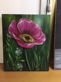 a painting of a pink flower sitting on top of a wooden table