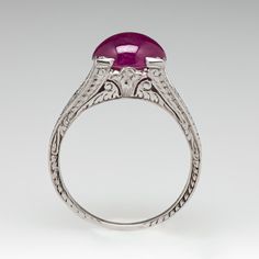 This captivating ring features a pierced and engraved design with milgrain details and is centered with an oval, ruby cabochon, weighing 2.53 carats, in a four-prong setting. The ring measures 7.1mm at the top, rises 7.9mm above the finger, tapering to 1.1mm wide and 0.7mm thick at the base of the shank. This ring is currently a size 5. Luxury Ruby Ring Oval Cabochon, Luxury Cabochon Ruby Ring For Anniversary, Luxury Ruby Ring With Oval Cabochon, Fine Jewelry Ruby Cabochon Ring In White Gold, Fine Jewelry Cabochon Ruby Ring In White Gold, Luxury Silver Ruby Cabochon Ring, Oval Ruby Ring In Platinum For Formal Occasions, Fine Jewelry White Gold Ruby Ring With Cabochon, Formal Oval Ruby Ring In Platinum