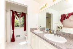 a bathroom with two sinks and a large mirror in it's center, surrounded by red curtains