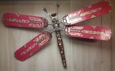 a pink dragonfly made out of skis and other items on a wooden surface