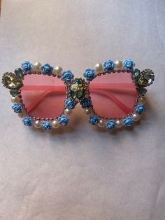 Oversized pink lens glasses. They have been hand decorated with a blue roses, pearls, rhinestone necklace and a gold drop earring.  I post internationally. dm for details.  Hand made one of a kind. Excess glue on the back is because of the hand making process and is to make sure all embellishments are on securely.  I also do custom orders. Message for details, I have a wide range of recycled embellishments for glasses including deconstructed costume jewellery, buttons, pearls and pins. I have mu Marie Antoinette Cake, Fashion Eye Glasses, Hand Making, Pink Sunglasses, Blue Roses, Drop Earring, Gold Drop Earrings, Marie Antoinette, Rhinestone Necklace