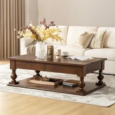 a living room with a couch, coffee table and flowers in vases on it