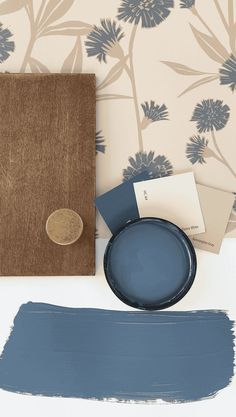 the blue paint is next to an empty plate and some papers on a white table