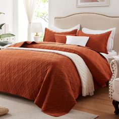 a bed with an orange bedspread and white pillows