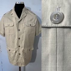 Lovely beige over shirt - jacket - safari style - open neck . 5 buttons - 4 pockets - short sleeve - epaulettes .2 vents on either side at hem ... see pics ..  Fabric has a check slub running through size label says 40"/42"... medium / large depending on desired fit .. see measurements  pit to pit 23"(46") length 31" shoulder to shoulder 18.5"  condition is great Classic Collared Short Sleeve Shirt With Pockets, Classic Short Sleeve Shirt With Pockets, Classic Short Sleeve Collared Shirt With Pockets, Khaki Collared Camp Shirt With Pockets, Beige Camp Collar Shirt With Buttons, Khaki Short Sleeve Button-up Shirt, Short Sleeve Khaki Shirt With Buttons, Collared Summer Outerwear With Button Closure, Summer Collared Outerwear With Button Closure