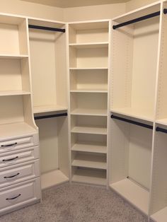 an empty walk in closet with white shelves and drawers