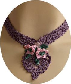 a purple crocheted necklace with flowers on it