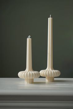 two white candles sitting next to each other on a table